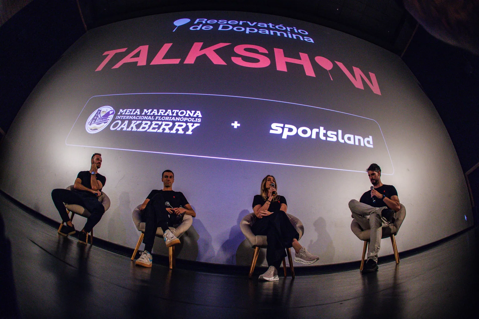 Talk show Reservatório de Dopamina no cinema, telão com as marcas Meia Maratona Oakberry e Sportsland